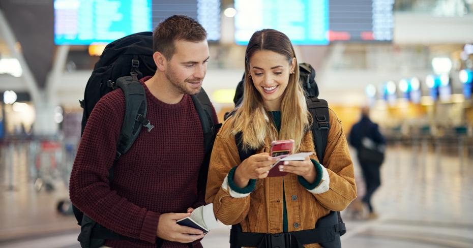 Para na lotnisku szukająca czegoś w telefoni